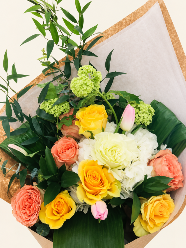 Bouquet de roses jaunes et pêche avec tulipes roses sur fond neutre