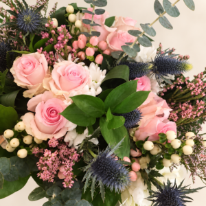 Bouquet de roses roses, fleurs blanches et chardons bleus sur fond neutre