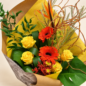 Bouquet Nathalie avec roses jaunes et gerberas orangés dans un emballage doré sur fond neutre