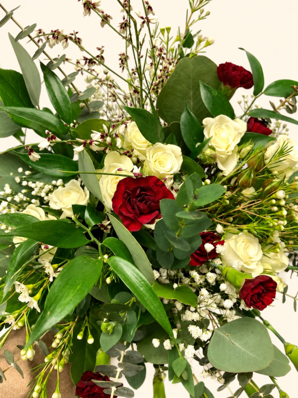 Bouquet sauvage de roses ivoire et bourgogne avec eucalyptus sur fond crème pâle