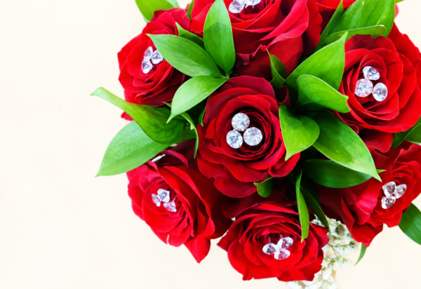 Bouquet de roses chic rouges avec pierres décoratives et feuillage sur fond ivoire