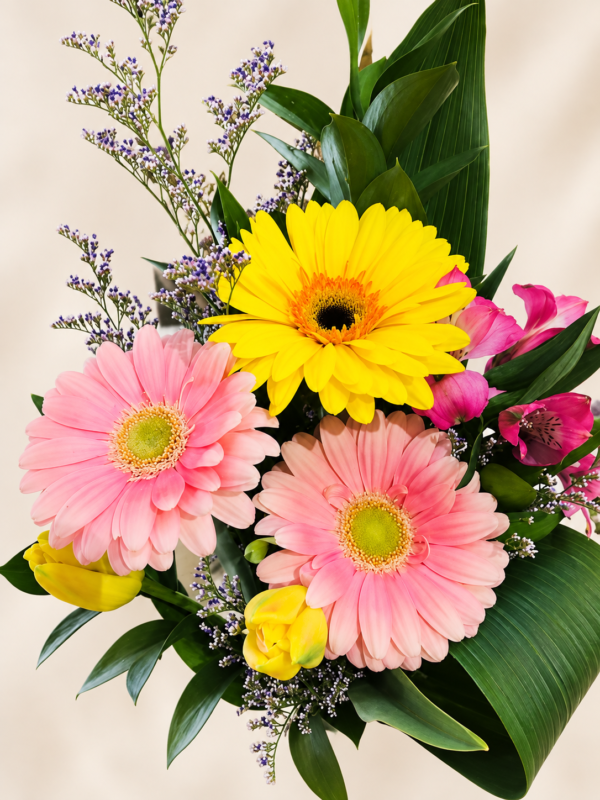 Bouquet coloré avec un gerbera jaune et deux gerberas roses sur fond crème pâle
