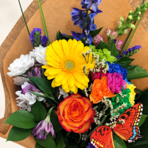 Bouquet de fleurs Le magnifique avec gerbera jaune, rose orangée et papillons décoratifs sur fond crème pâle