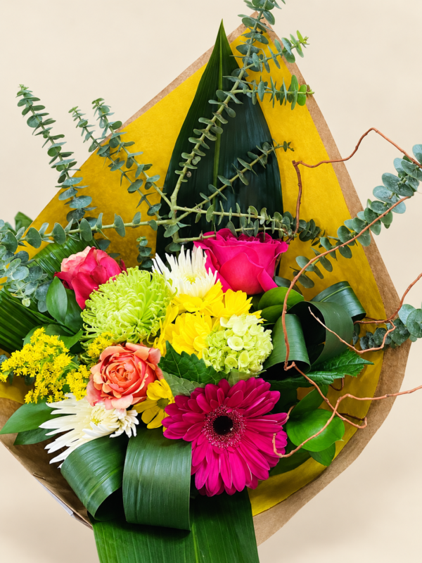 Bouquet Sabrina coloré dans son emballage jaune et kraft sur fond crème pâle