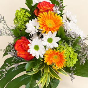 Bouquet marguerites gerberas avec roses orangées, fleurs blanches et feuillage sur fond crème pâle