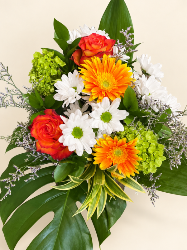 Bouquet marguerites gerberas avec roses orangées, fleurs blanches et feuillage sur fond crème pâle