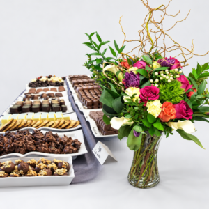 Bouquet de fleurs colorées et plateaux de chocolats sur fond gris pâle