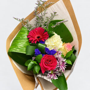 Bouquet de fleurs colorées emballé de papier kraft et de papier de soie sur fond pâle