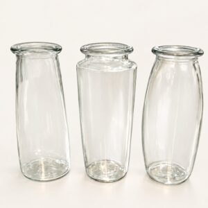 Trois vases transparents pour bouquets de 50 $ à 125 $, sur fond ivoire