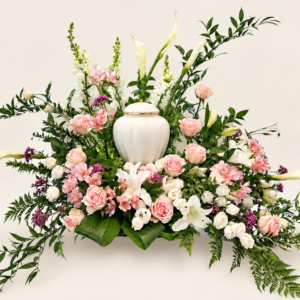 Montage floral rose et blanc autour d’une urne blanche sur fond neutre